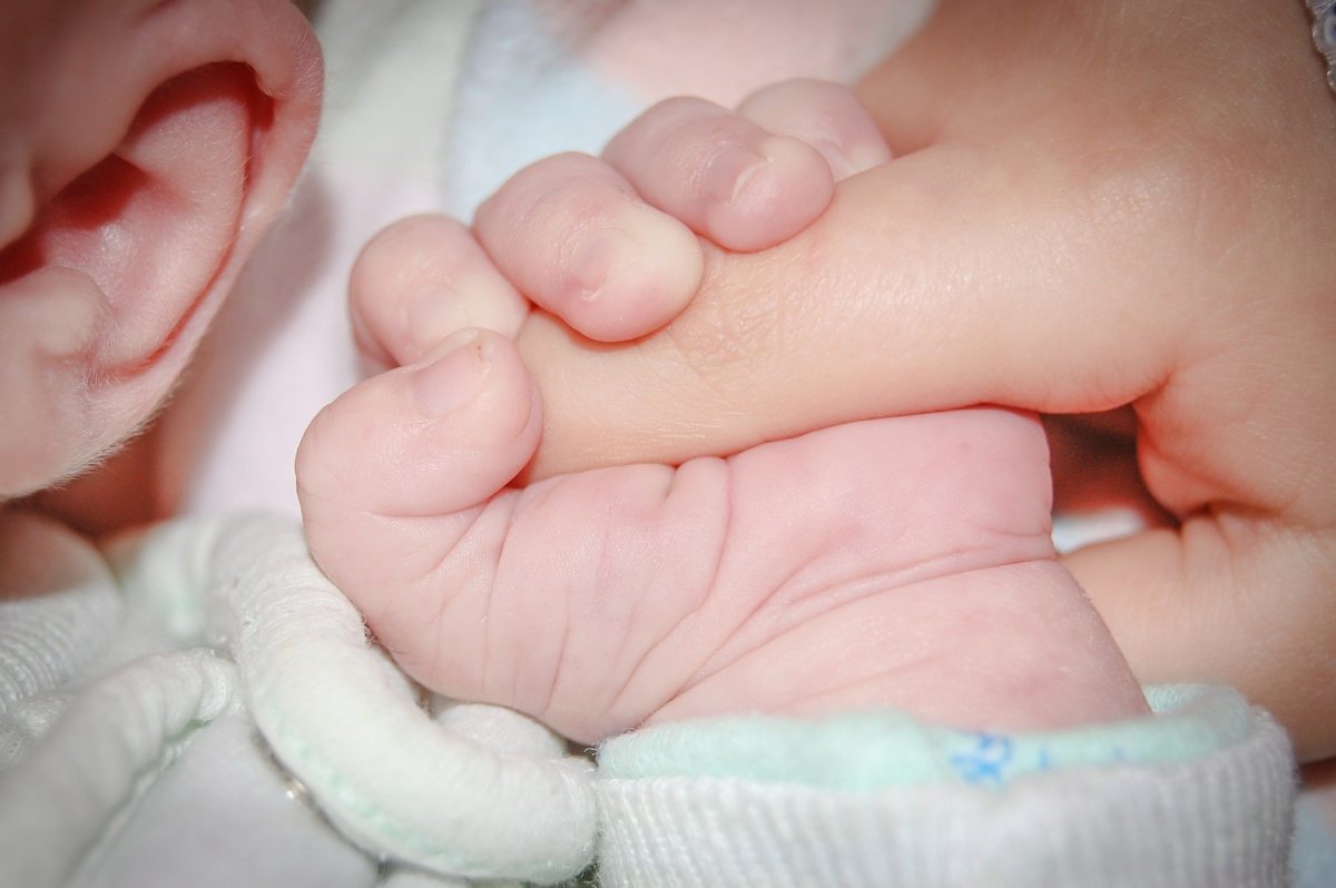 dłoń noworodka trzymająca palec dorosłego