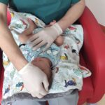 badanie noworodka - dłonie na głowie